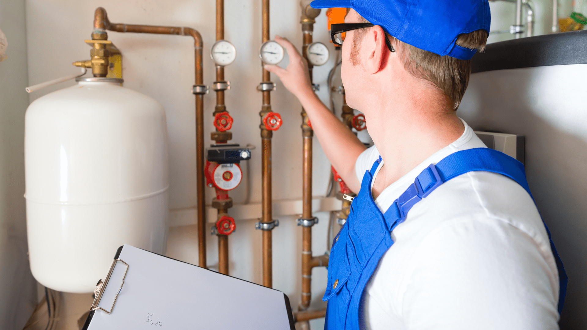 Hausmeister prüft Heizungsanlage mit Klemmbrett und Werkzeug